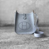 Hermès Bleu Glacier Evelyne 16 Amazone Bag, a compact crossbody in Clemence leather with signature perforated H logo and canvas strap.