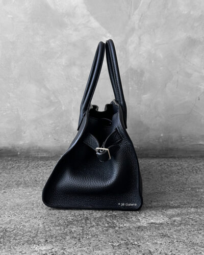 The Row Black Soft Margaux Top-handle bag in matte grained calfskin leather with belted gusseted side panels and interior toggle closure